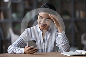 Smiling Indian woman use cellphone texting laughing