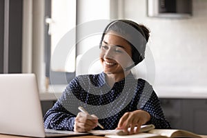 Smiling Indian woman wearing headset involved in online lesson