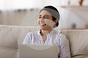 Smiling Indian woman work on laptop making plans