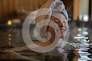 smiling individual with a towel on their head lounging in an onsen