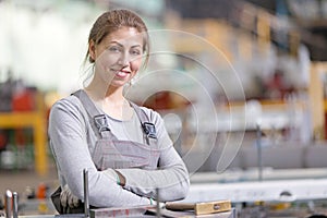 Smiling industrial female worker at workplace on manufacture workshop background