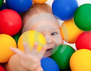 Smiling infant lying among colorful balls