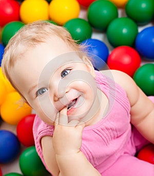 Smiling infant playing among colorful balls