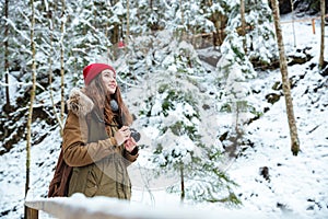 Smiling inspired woman photographer taking photos at forest in winter
