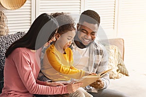 Smiling international parents teach child to read