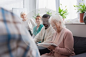 Smiling interracial pensioners using digital tablet