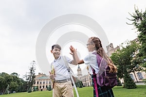 Smiling interracial schoolkids giving high five