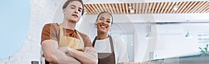 Smiling interracial sellers in aprons looking