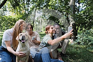 Smiling interracial teenagers using smartphones near