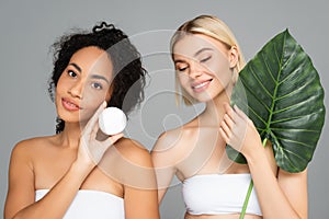Smiling interracial women posing with cosmetic