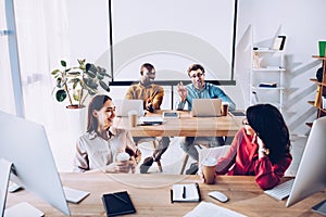 smiling interracial young business people talking during work