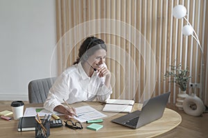 Smiling Italian female employee in wireless headset taking part in online meeting with collegues