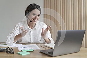 Smiling Italian young businesswoman in headset talking with colleagues during online meeting