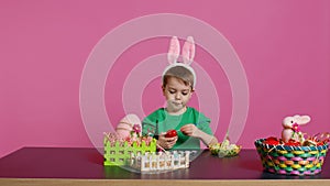 Smiling jolly preschooler painting eggs and ornaments for easter festivity photo