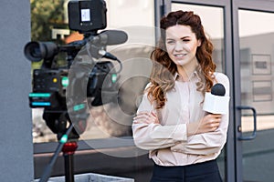 smiling journalist with microphone standing in front of digital