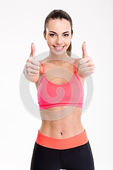 Smiling joyful fitness girl showing thumbs up with both hands