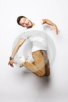 Smiling joyful man jumping on a white background.