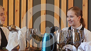 Smiling joyful waiters cleaning glasses and talking in restaurant