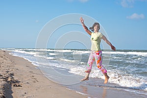 Smiling joyful woman is jumping in surf