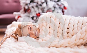 Smiling joyful woman lying under a warm blanket