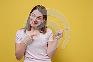 Smiling joyful woman pointing at copy space for advertisment or promotional text