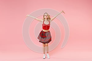 Smiling joyful young blonde woman girl in red sexy clothes posing isolated on pastel pink background studio portrait