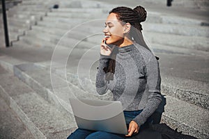 Smiling joyous lady with cornrows calling on the smartphone