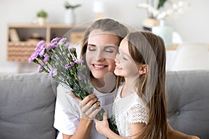 Smiling kid daughter giving flowers congratulating mom with moth