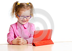 Smiling kid in glasses looking at mini tablet pc screen sitting photo
