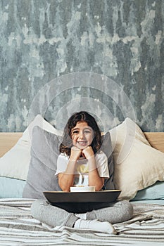 Smiling kid having a breakfast in her parents` bed