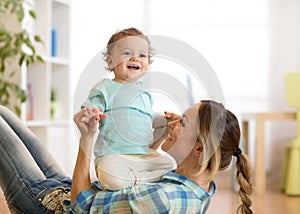 Smiling kid and mom having a fun pastime on floor in children room at home photo