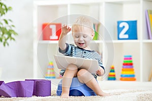 Smiling kid sitting on chamber pot with toilet paper