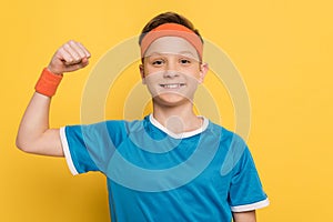 Smiling kid in sportswear showing strong gesture