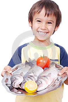 Smiling kid with three fresh fishes on table