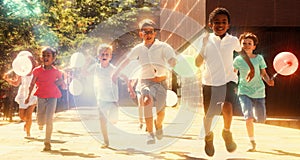 Smiling kids with balloons running in race and laughing at street