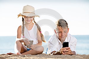 Smiling kids on beach with phone in hands