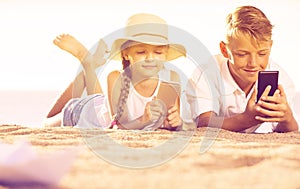 Smiling kids on beach with phone in hands