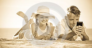 Smiling kids on beach with phone in hands