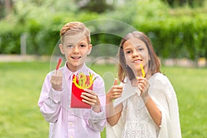 Smiling kids eating fresh vegetables in nature Ã¢â¬â happy children holding colorful peppers sliced in form of french fries