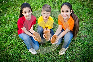 Smiling kids at green grass holding a little rabbits, easter con