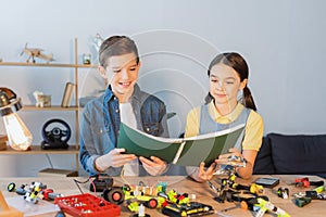 Smiling kids holding notebook near robotic