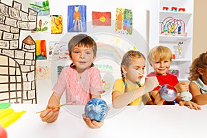 Smiling kids paint New Year balls for Xmas tree