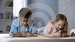 Smiling kids playing online games in mobile application, addiction to gadgets