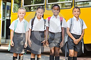 Smiling kids standing together in front of school bus