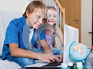 Smiling kids surfing internet on laptop