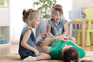 Smiling kids and mom having a fun pastime on floor in children room at home photo