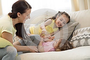 Smiling kids and mom having a fun pastime on sofa in living room at home photo
