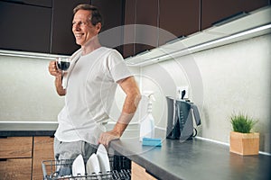 Smiling kind adult male drinking his morning coffee