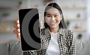 Smiling Korean Female Holding Big Smartphone With Blank Blank Screen At Home