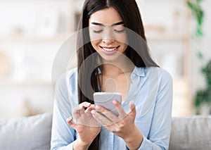 Smiling korean girl using smartphone at home, checking incoming emails